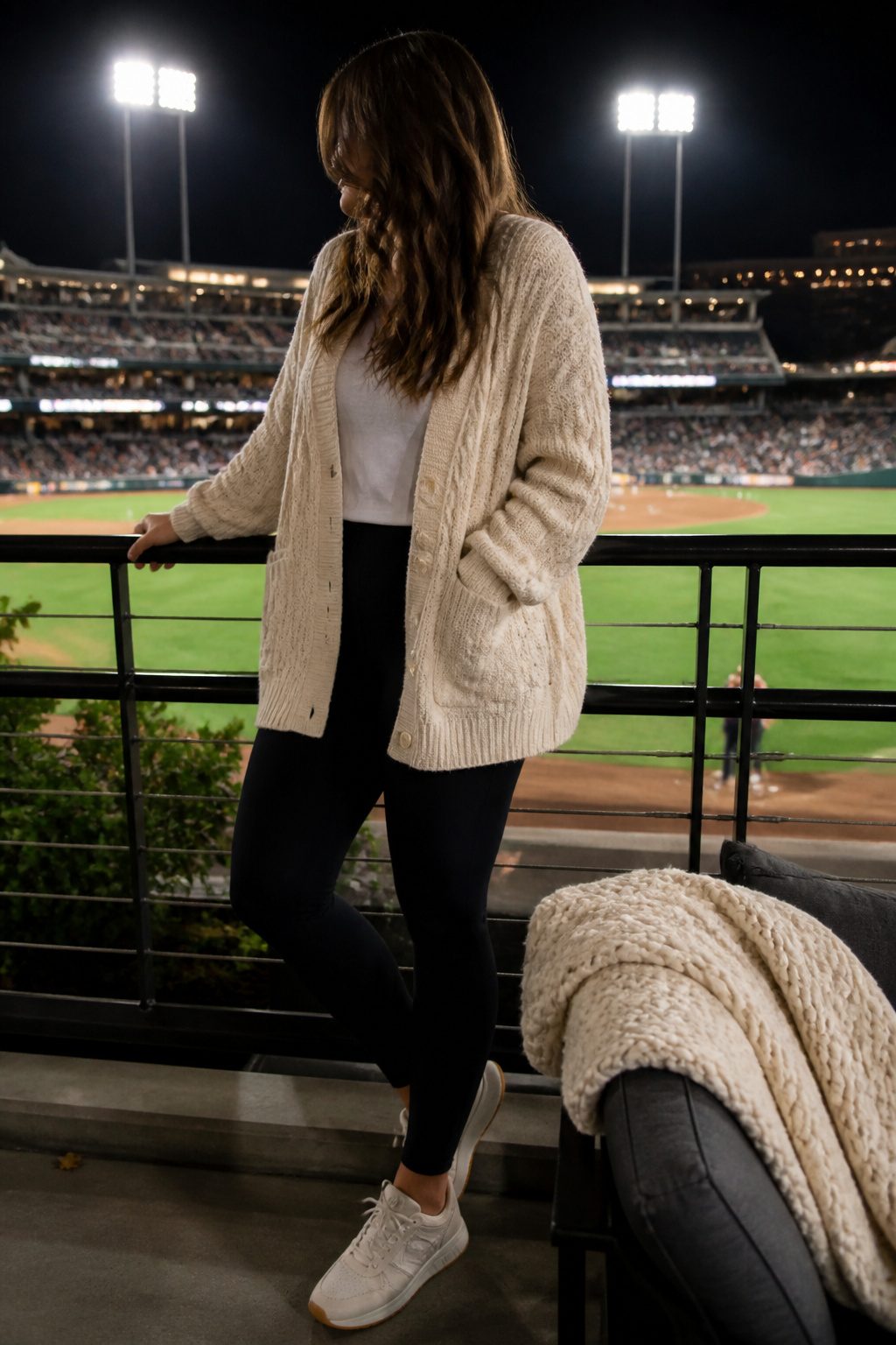 Model in a cardigan over leggings, framed by warm stadium lights.