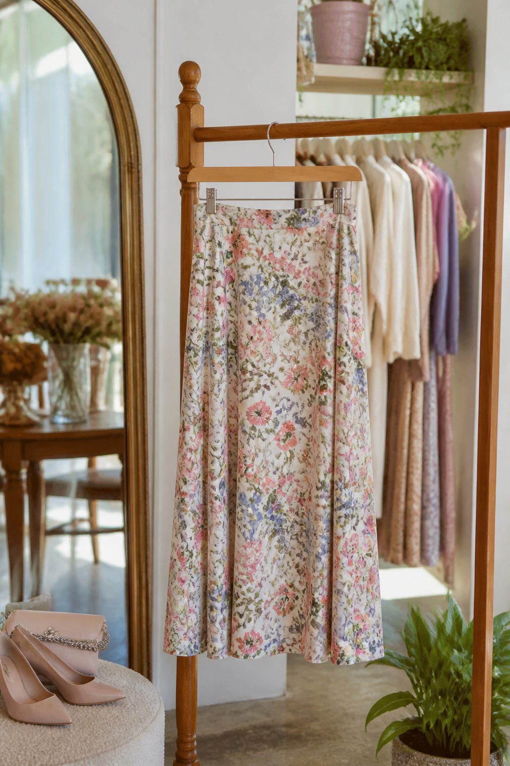 A floral midi skirt hanging on a vintage wooden rack in a boutique.