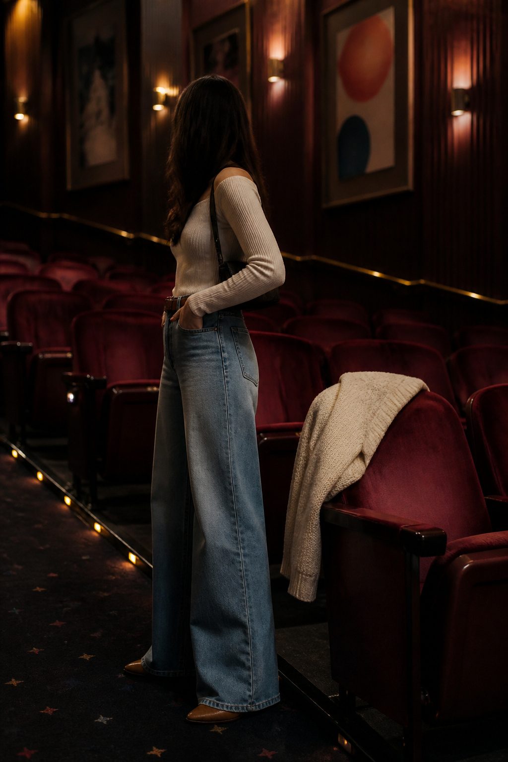 Model wearing relaxed jeans and a fitted top inside a classic cinema.