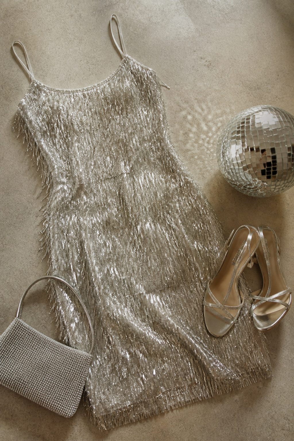 Disco Party Outfit Ideas, Types & How to Wear Them in 2026 6 A mini dress with fringe details displayed in natural light.
