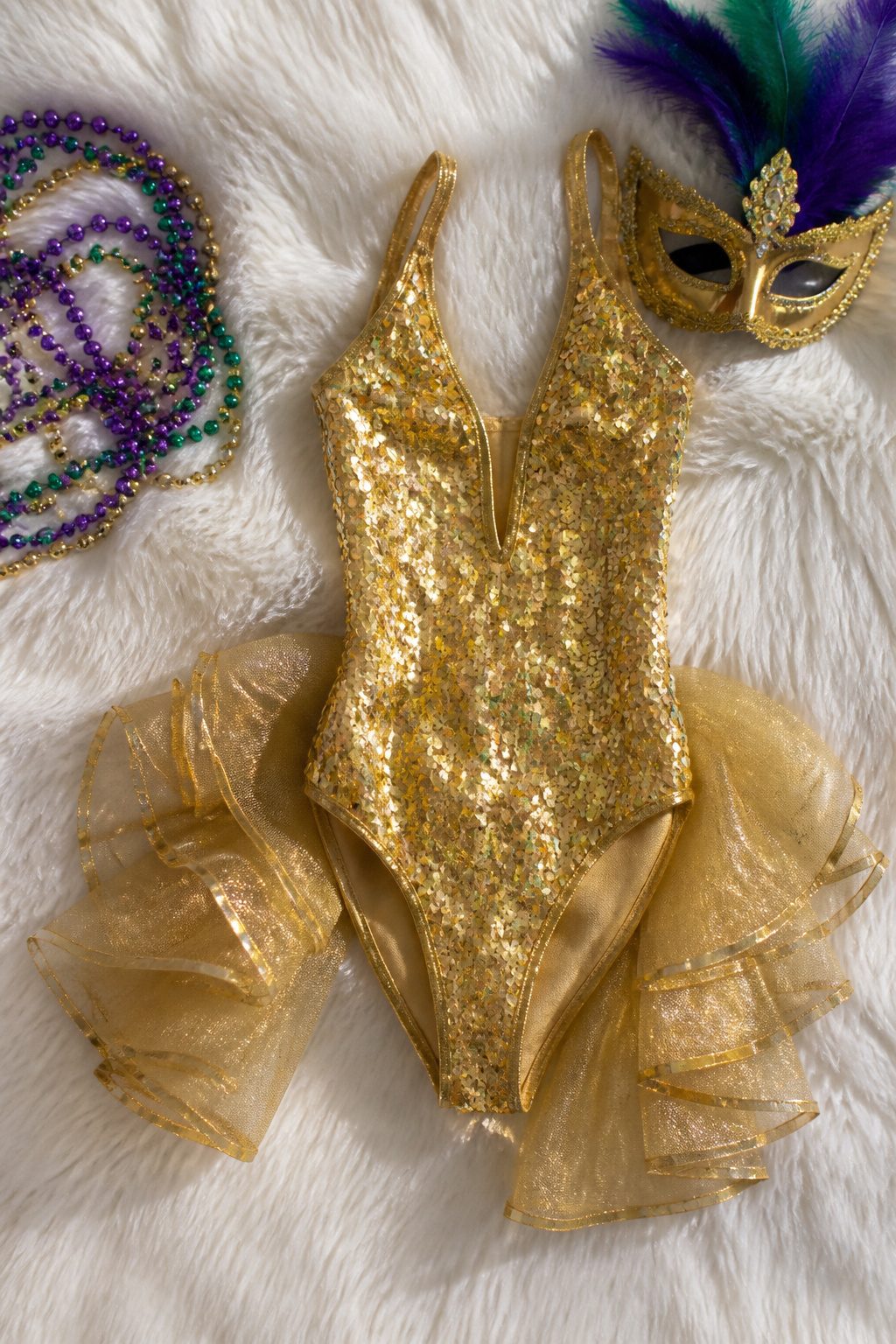 Gold sequin leotard with a ruffle tail shown on a flat surface.
