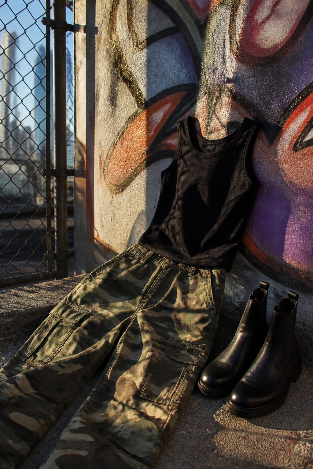 25 Morgan Wallen Concert Outfit Ideas for 2026 Shows 25 Camo cargo pants and black tank top on a concrete backdrop.