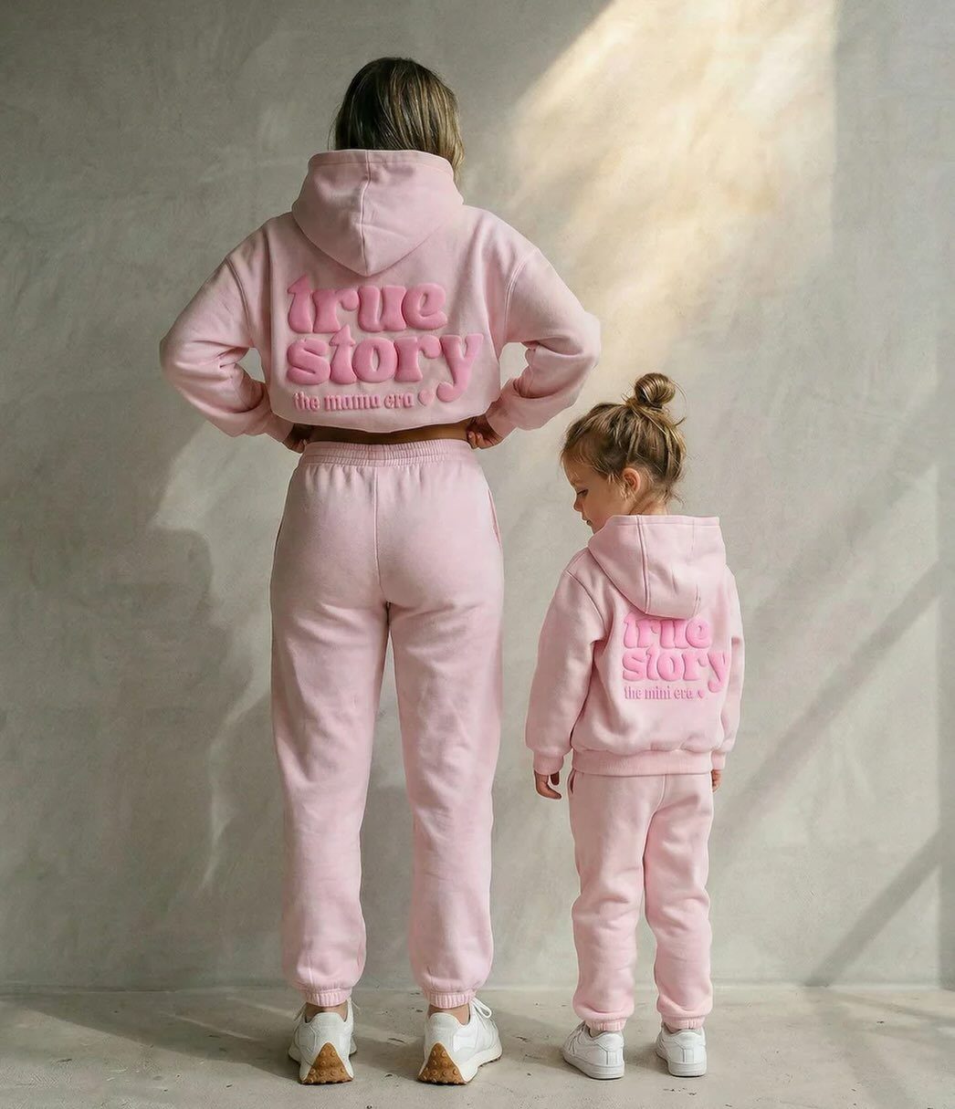 Woman and toddler girl wearing matching pink two-piece hooded sweatshirt and sweatpants sets.